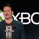 Phil Spencer stands in front of Xbox logo.